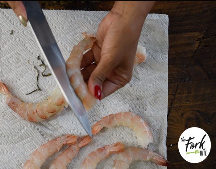 Remove the sharp pointed shell from the tails. Peel the prawns but leave the last sections of the shell above the tails. Pierce the back of the prawns with a bamboo skewer and remove the sand veins.