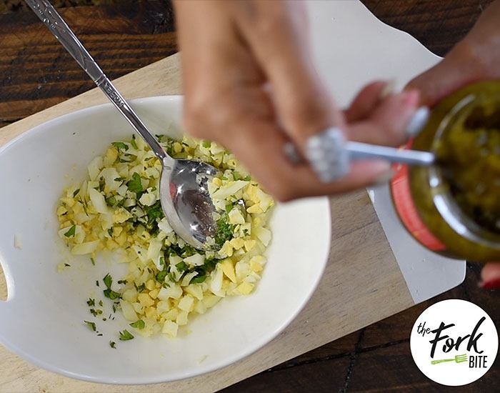 Slice the hard-boiled egg crosswise with an egg slicer. Remove and slice it lengthwise across the initial slices. Rotate it by 90 degrees and slice it lengthwise again. Put the finely chopped boiled egg into a bowl.