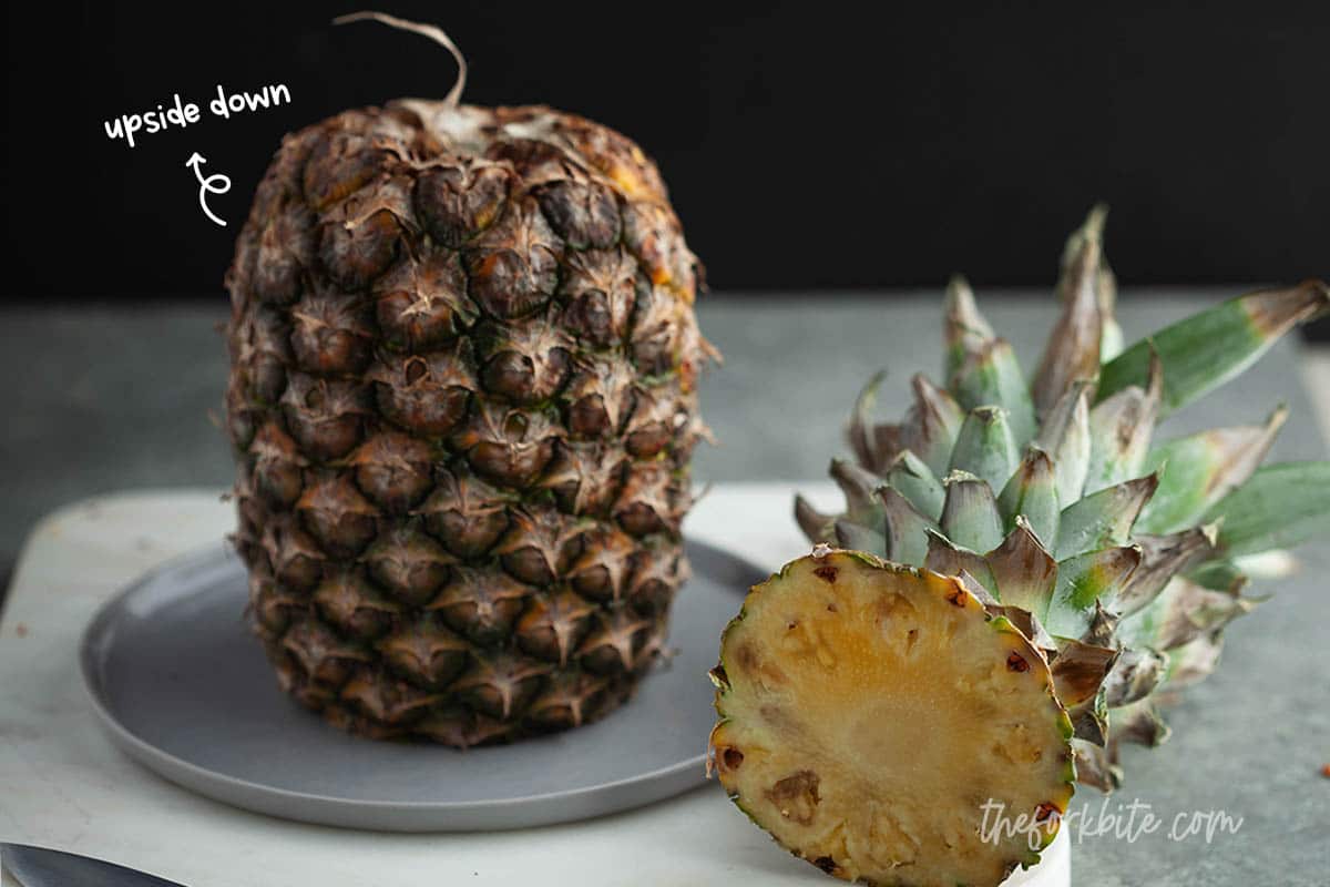 A "topsy-turvy" pineapple, balanced on its stem, (where the leaves sprout out from), will ripen a little. This is after all the way it grows in nature.