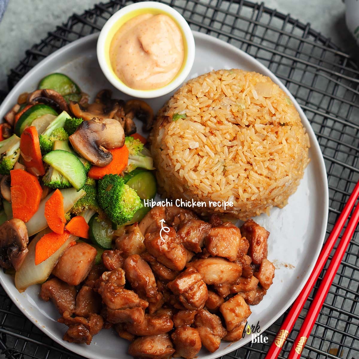 This copycat Hibachi Chicken recipe is made of savory chicken bites with sautéed vegetables, served over fried rice and topped with yum yum sauce.