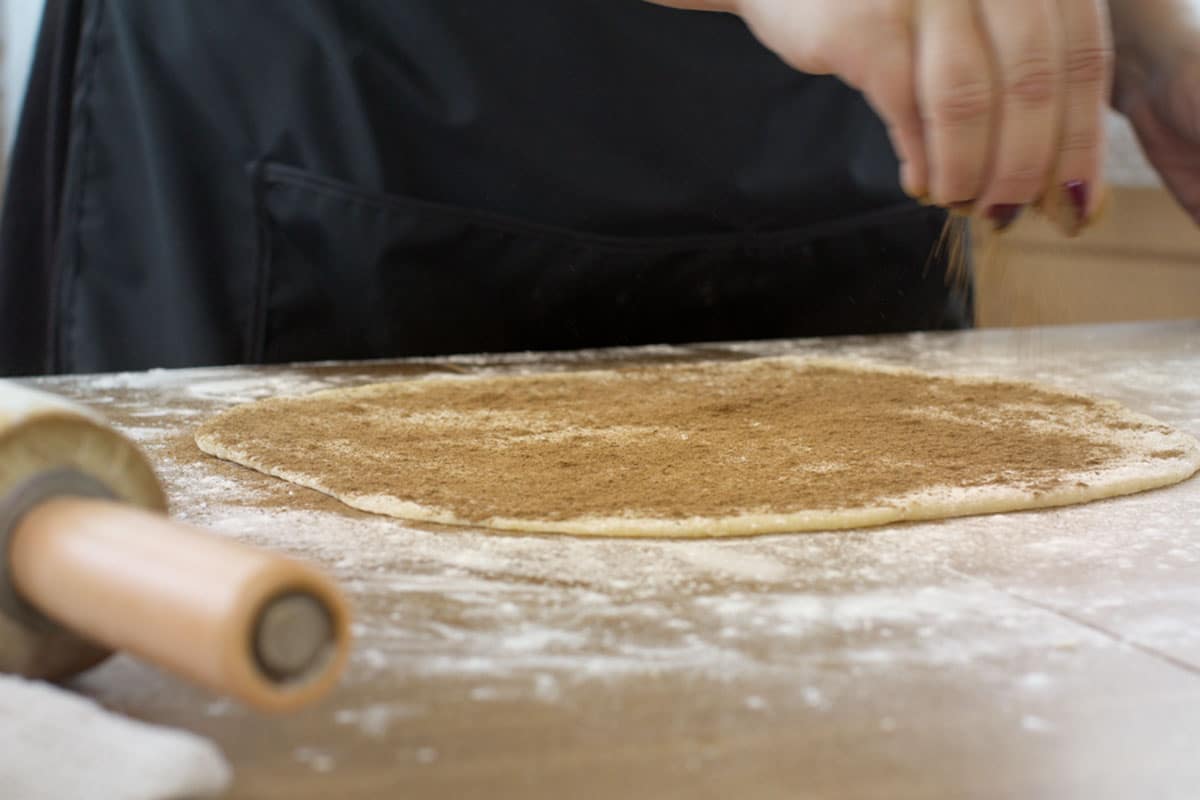 Using a rubber spatula or knife, gently spread the soft and butter across the entire surface of the rolled out dough. Sprinkle evenly with brown sugar and cinnamon.