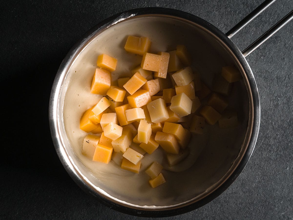 Add the cheese cubes. Doing this helps soften the cheese more quickly and keep it from burning to the bottom of the pan. The cheese will slowly begin to melt but make sure to stir often.