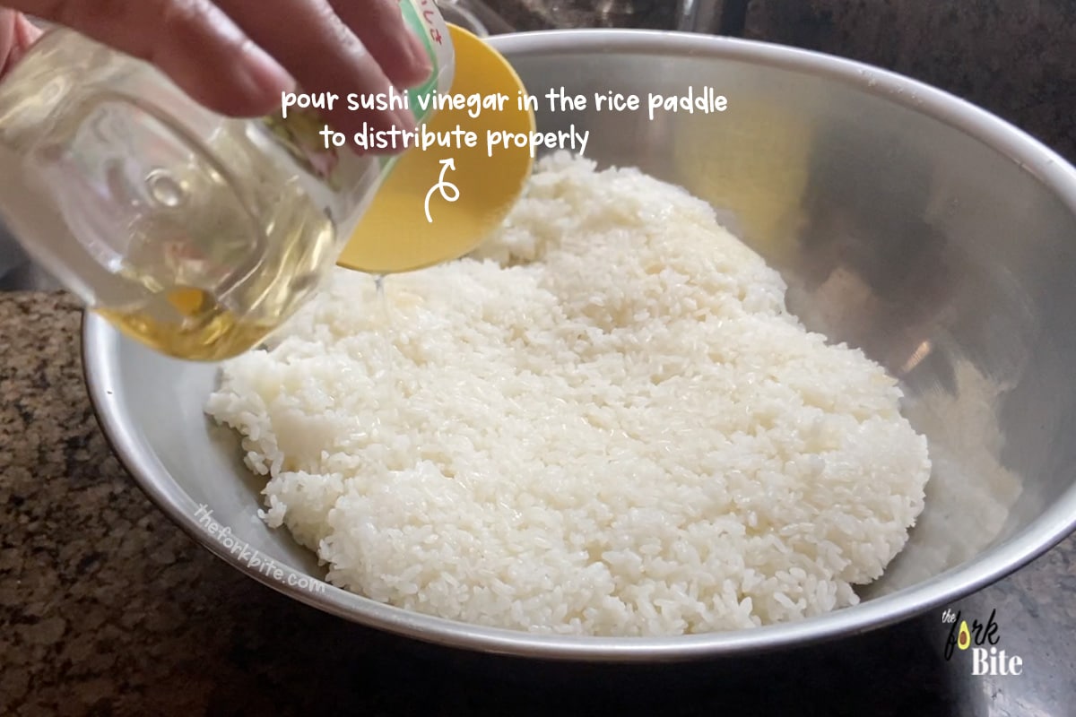 If you pour the vinegar straight into the rice, it won't distribute properly, so it's best to use your non-stick paddle or wooden spoon and pour the vinegar over the back of the implement, spreading it evenly across the top of the rice.