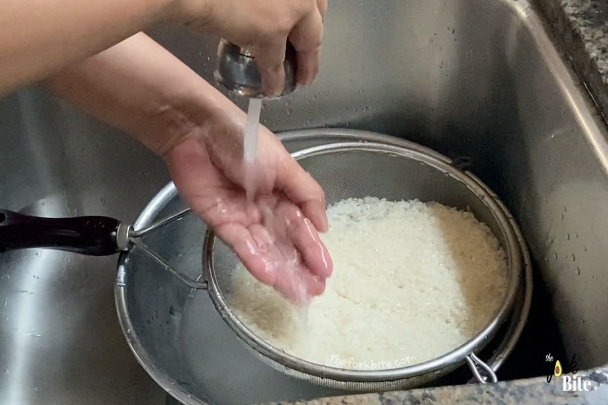 Tip the rice into a sieve and wash it thoroughly under the cold water tap in your kitchen sink. This is to wash out the excess starch.