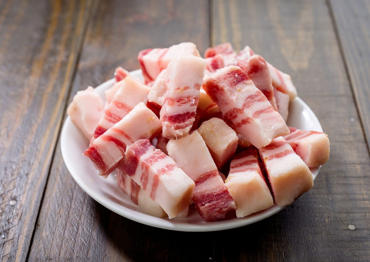 You can cut lardons from frozen bacon with a very sharp knife by slicing horizontally across a clump of rashers. Transfer the bacon from the freezer onto a chopping block or board and slice away.