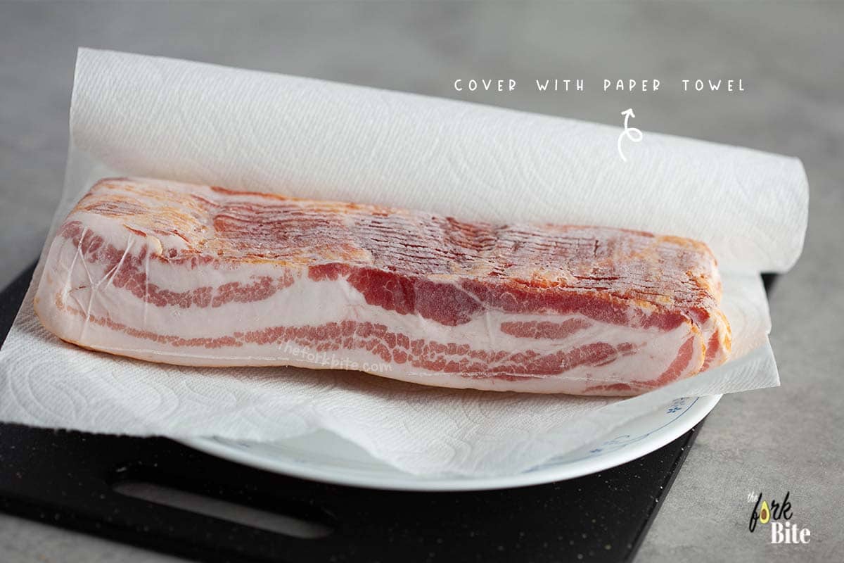 Take the bacon out of the freezer, remove it from its packaging, and wrap it in a paper kitchen towel.