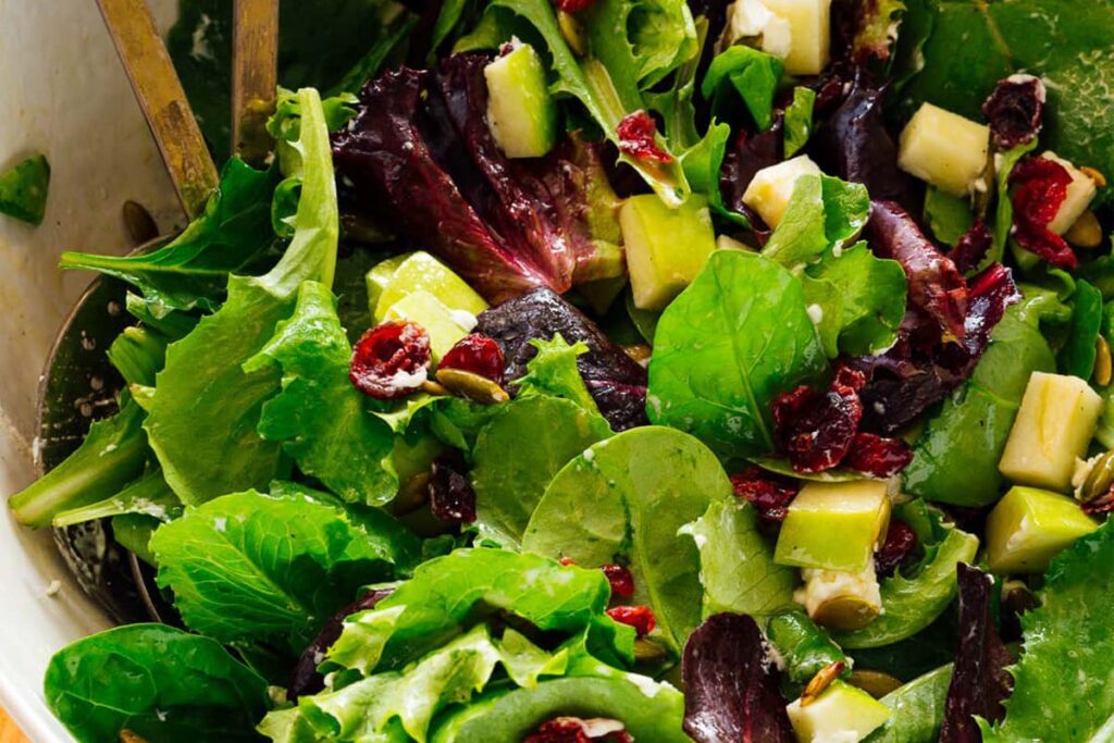 What goes with beef stew is something healthy. This type of green salad has Granny Smith apples, creamy goat cheese, spring greens, and sweet, dried cranberries.