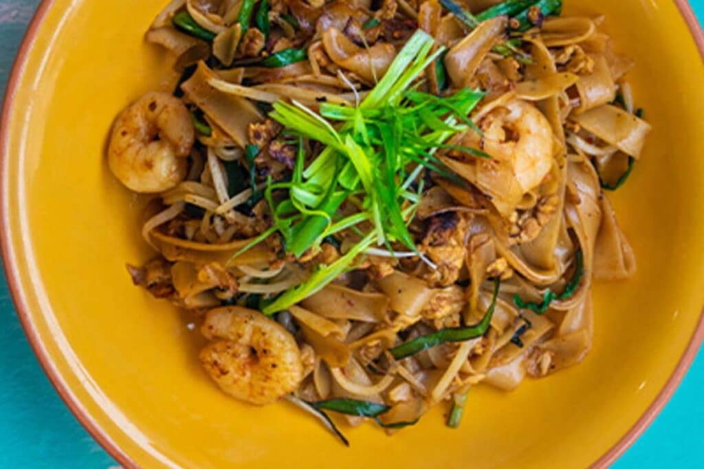 Kway Teow rice noodles are similar to fettuccini but thicker and wider.  Being more substantial, they carry sauce better, creating velvety noodle dishes, which you often see in Singapore on street food stalls.