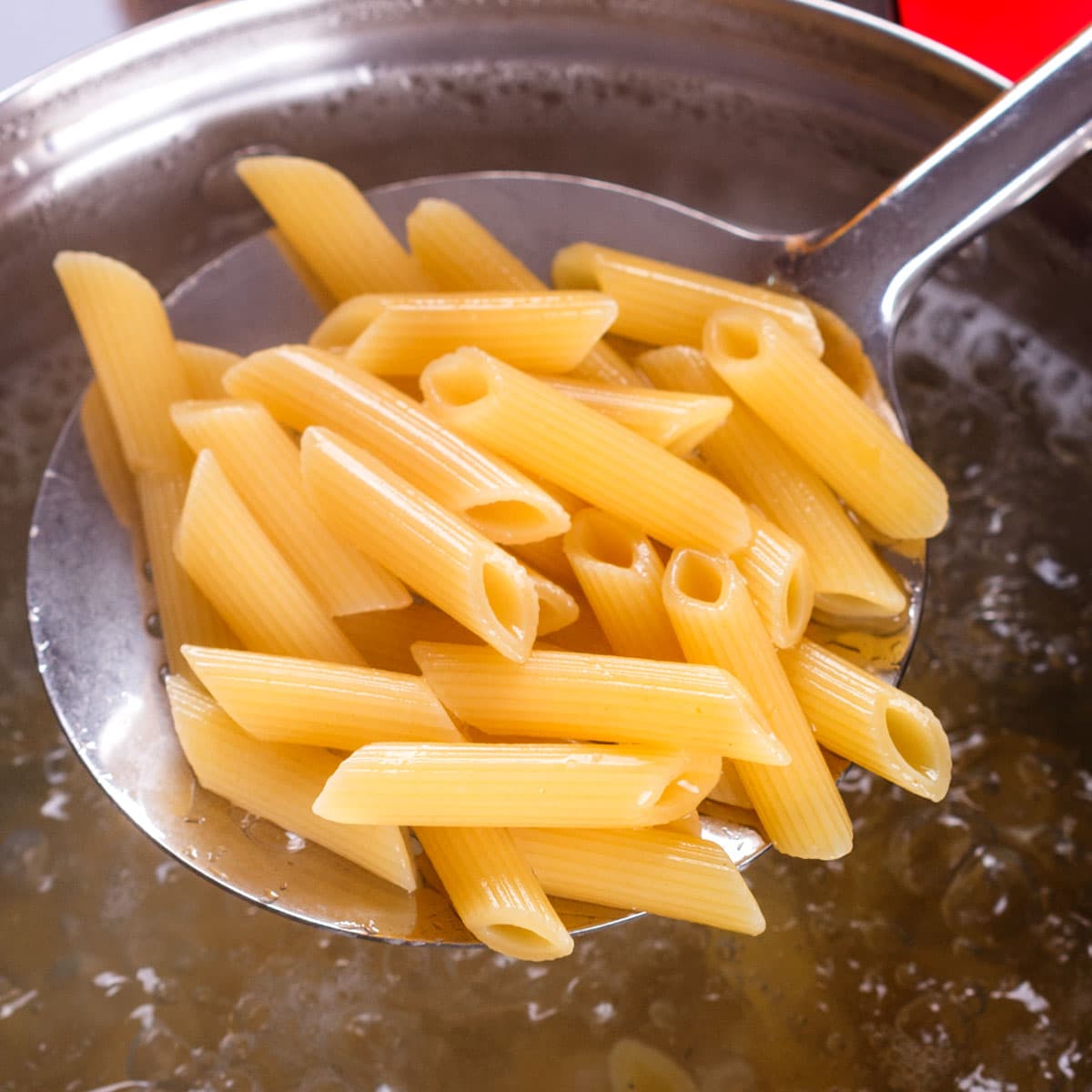 Using a slotted spoon works best for me. Not only does it allow you to quickly and easily remove the pasta from the boiling water, but it also allows some of the hot cooking liquid to drip off before adding it to the pan with the sauce.