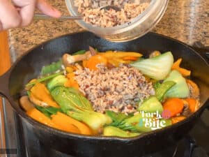 Add the baby bok choy, carrots, snap peas, shiitake mushrooms, shimeji mushrooms, and bell pepper to the pan. Stir-fry the vegetables for 30 seconds or until they are tender-crisp. Add the red rice + Quinoa.