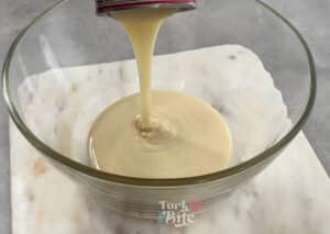 Start by whisking together sweetened condensed milk and water with an electric mixer.