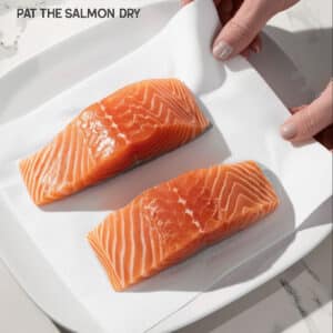 Patting raw salmon fillets dry with a paper towel