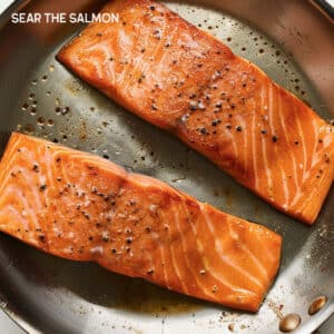 Salmon fillet, skin-side down, sizzling in a hot pan.