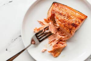 Close-up of perfectly cooked fresh salmon flaked with a fork, showcasing a chunky texture.