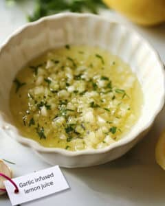 Minced garlic soaking in a bowl of lemon juice for a homemade aioli recipe.