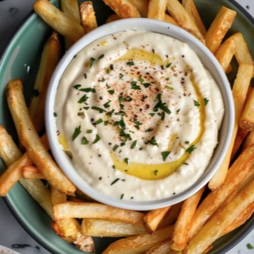A bowl of creamy Roasted Garlic Aioli, with a drizzle of olive oil and fresh herbs on top
