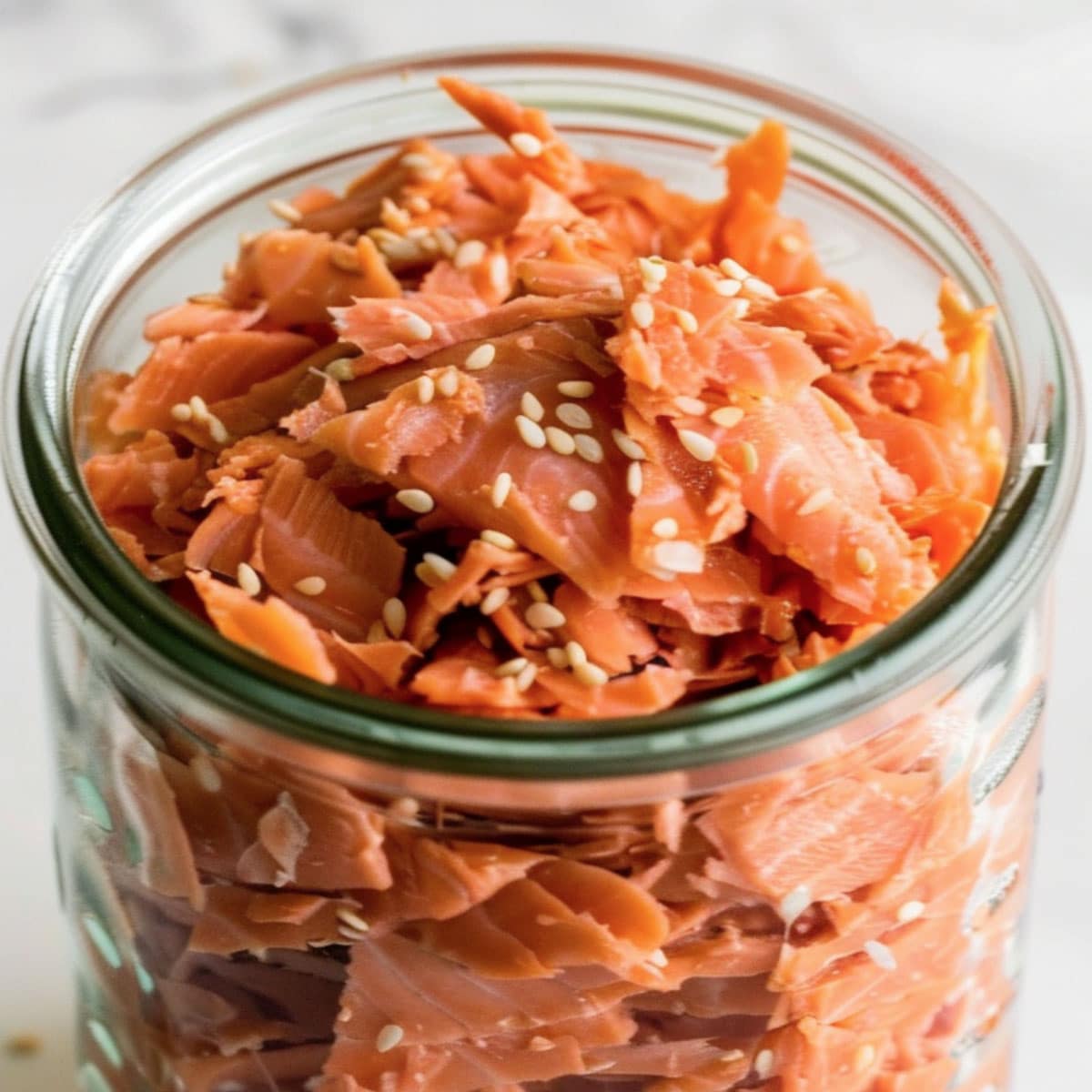 Image of a glass jar overflowing with homemade salmon flakes; ready for use in salads and sandwiches.