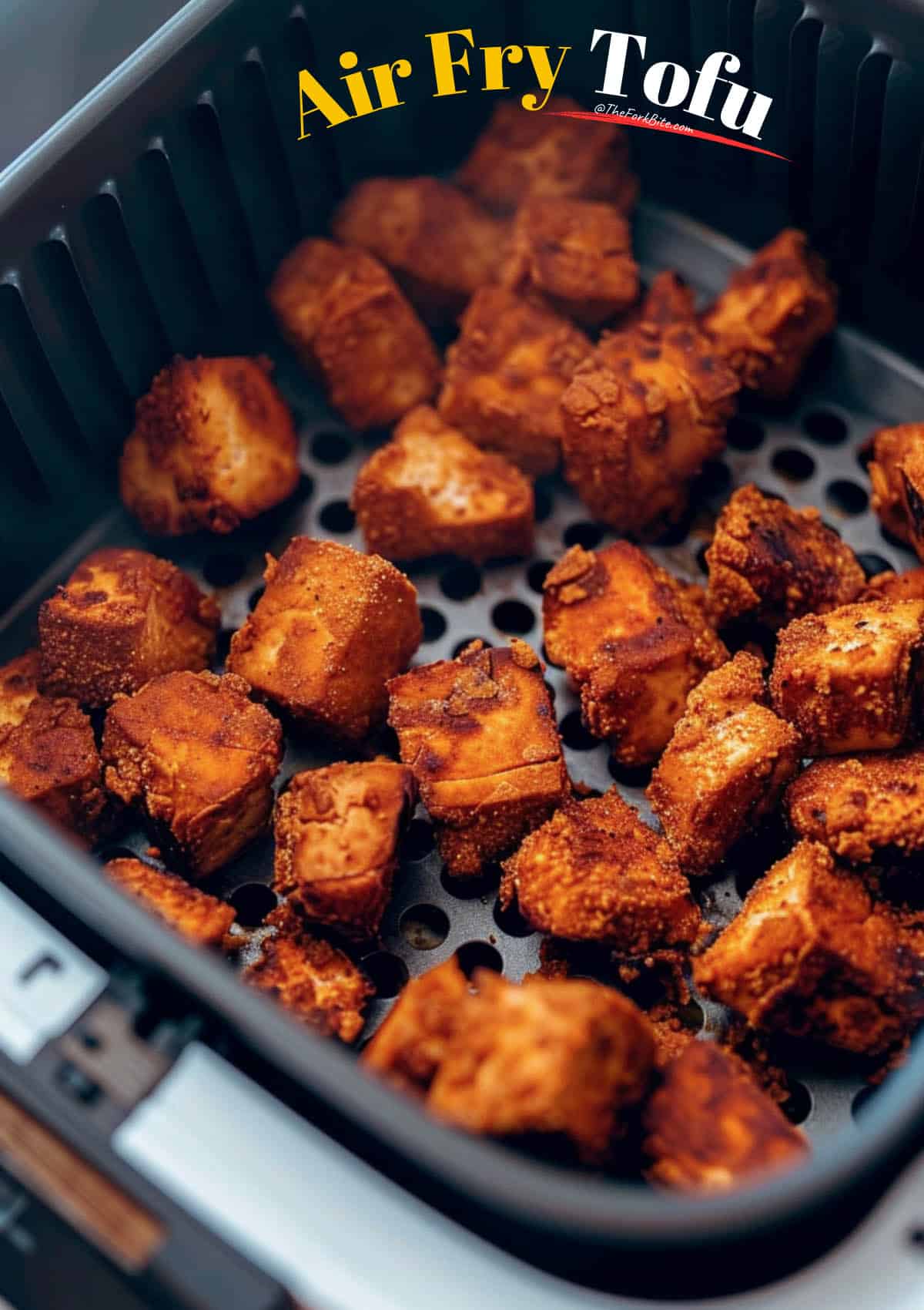 Air fryer basket filled with coated tofu, leaving space between pieces for even crisping.