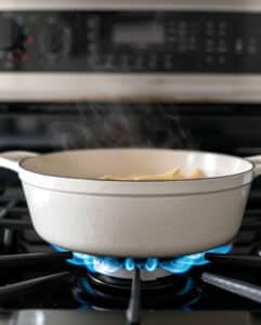 A large pot of boiling water with pasta cooking inside; the noodles are well-separated and not sticking together.