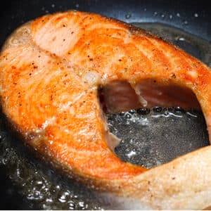 A close-up photo of overcooked, dry salmon fillet with a pale, tough texture.