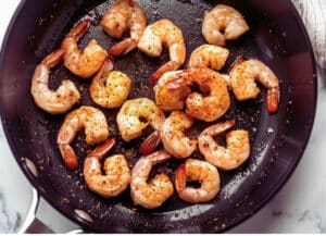 Shrimp sizzling in a hot skillet, starting the process for a delicious Shrimp Étouffée.
