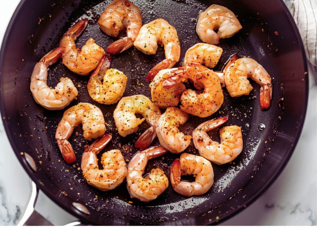 Shrimp sizzling in a hot skillet, starting the process for a delicious Shrimp Étouffée.